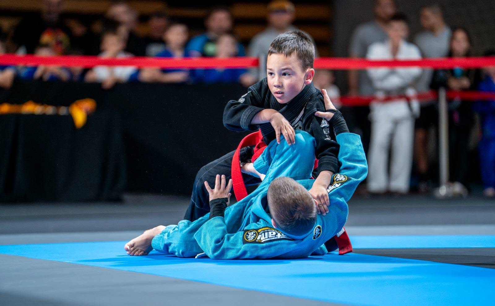 Dijete u crnom kimonu kontrolira protivnika u parteru na jiu jitsu natjecanju