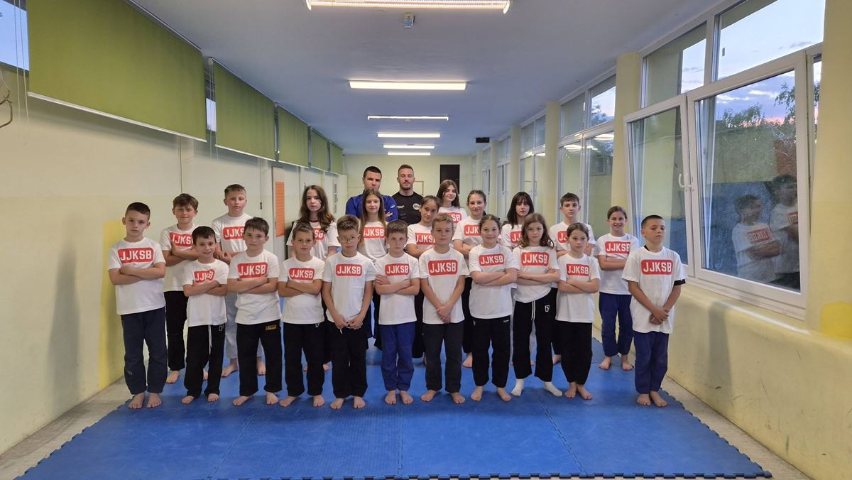 Grupna fotografija djece u klupskim majicama JJKSB s trenerom na plavim strunjačama