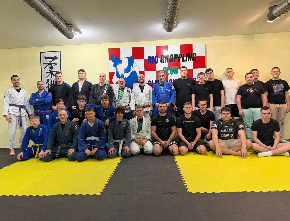 Grupna fotografija polaznika različite dobi u kimonima i sportskoj odjeći ispred zida s logom Rio Grappling Cluba